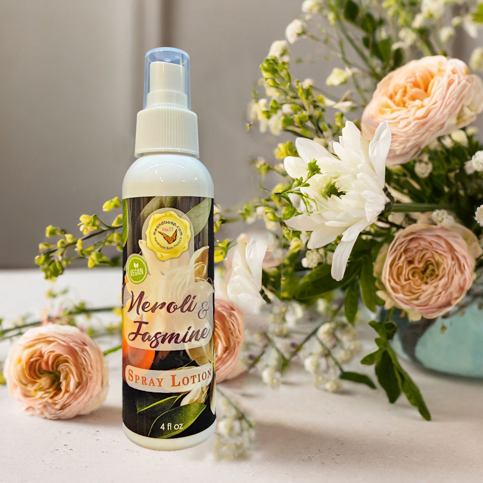 Michigan Soap Co-op's Neroli and Jasmine lotion shown with peach flowers in a vase flowing onto table